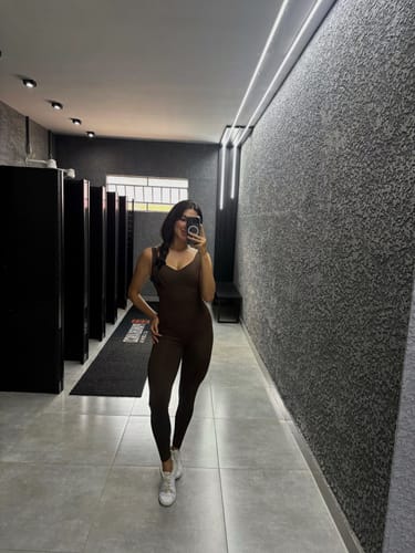 Avaliadora mostrando o Macacão Fitness Marrom Coffee justo ao corpo em selfie no espelho.