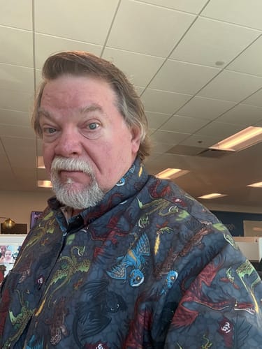 Reviewer wearing the "Scales 'n' Tails" short sleeve shirt, showing the colorful and detailed dragon print.