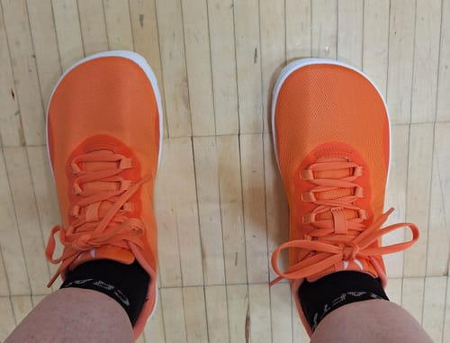 Arvostelijan kirkkaan oranssit Vaistoa Tahto -paljasjalkasalikengät jaloissaan, ylhäältä kuvattuna.