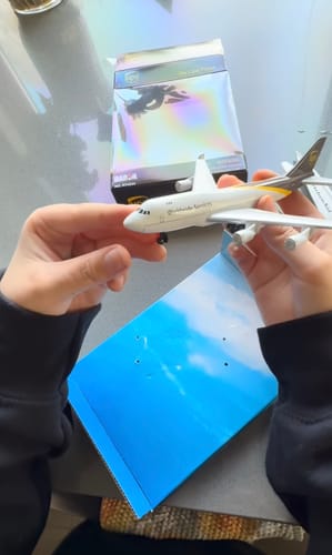 Reviewer holding the UPS Single Plane toy in their hands over the open box.