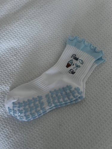 Customer's white Pilates & Chill sock with a light blue frilly cuff and flower-shaped grips on the sole.