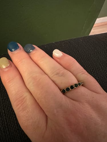 Reviewer wearing the gold-tone Emerald Beauty 18K Crystal Ring with a row of dark stones on their finger.