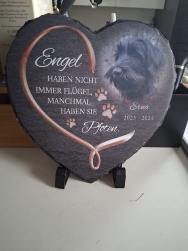 Ein Kunde zeigt das personalisierte Schieferherz mit dem Foto eines schwarzen Hundes und einem Spruch darauf.