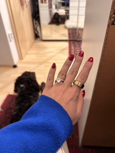 Reviewer showing their hand with the elegant Oval Solitaire Ring paired with a wide gold band.