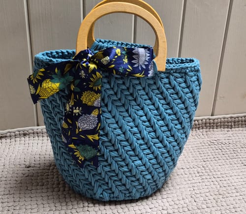 Customer's completed teal CrochetPark granny bag with wooden handles and a decorative scarf.