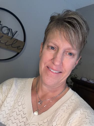 Customer wearing the DAISY BIRTH-FLOWER CHARM on a layered silver-toned necklace.