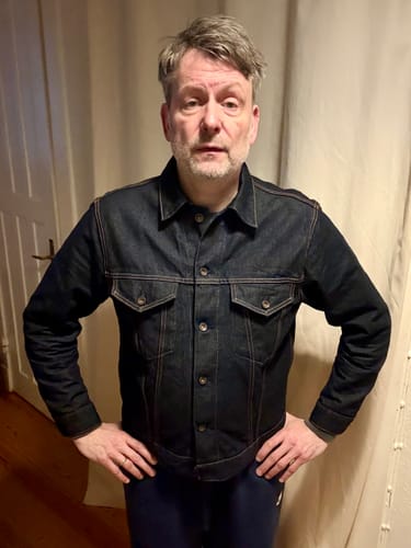 Customer wearing the dark blue Lot 601 Selvedge Denim Jacket indoors, standing with hands on hips to show the fit.