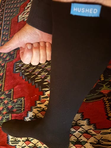 Customer's leg wearing a black Performance Eucalyptus Compression Sock, with their hand on the calf.