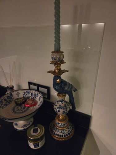 Recensent toont de Ilay Vogel Kandelaar met een groene kaars op een zwart aanrecht.