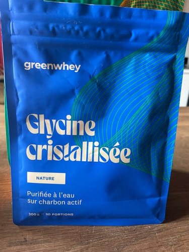 Photo d'un client montrant le sachet bleu de Glycine cristallisée sur une table en bois.