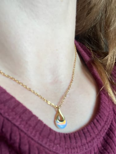 Close-up of a reviewer wearing the Tiffany White Stone Pendant Necklace, showing its dainty chain and iridescent teardrop pendant.