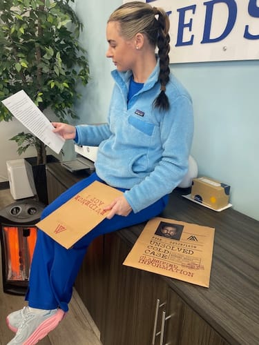 Reviewer in an office examines papers from the Unsolved Cold Case Files Game, with the evidence folders displayed.