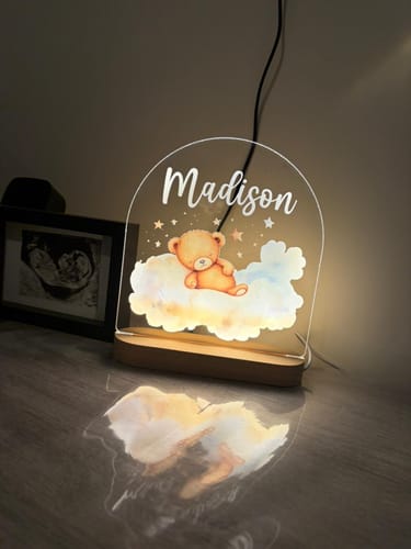 Recensent toont het verlichte Trustenbeertje nachtlampje, gepersonaliseerd met de naam 'Madison' op een tafel.