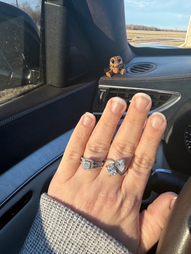 Reviewer's hand inside a car, wearing the silver-toned Navae Birthstone Ring next to another ring.