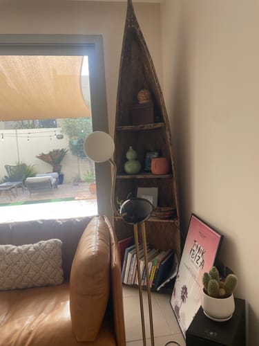 Reviewer's Flamingo Floor Lamp with gold tripod legs in a decorated living room corner next to a sofa.