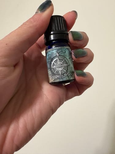 Customer's hand holding the small, blue Compass Rose bottle.
