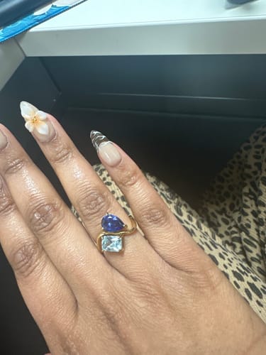 Reviewer's hand wearing the gold Navae Birthstone Ring with a dark blue pear-cut and a light blue radiant-cut stone.