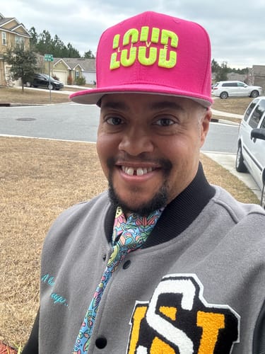 Reviewer smiling in the grey Star Wars varsity jacket, showing the embroidered text and 'SW' chenille patch.