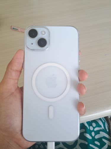 Customer's hand holding a white titanium iPhone 15 Plus with the transparent Anti Yellow Magsafe case fitted on it.