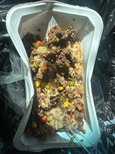 Reviewer's partially eaten Bison Shepherd's Pie, showing the ground meat and vegetables mixed in the container.