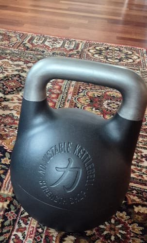 Customer's black competition-style Adjustable Kettlebell resting on a patterned rug.