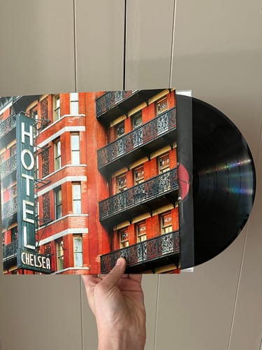 Reviewer holding a custom vinyl record with a glossy cover photo of a building and the black vinyl disc partially visible.