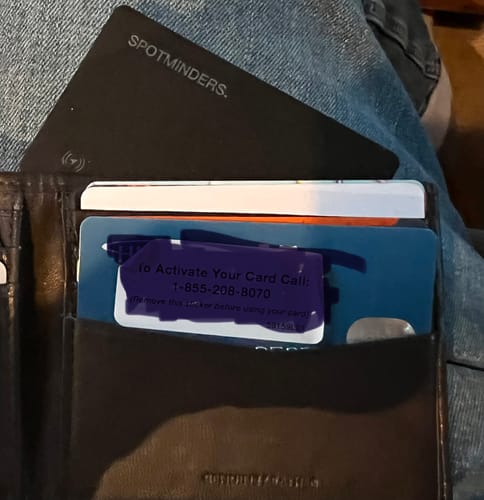 Customer's black SPOTMINDERS Tracking Card shown inside a wallet alongside other cards.