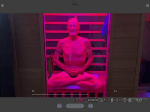 Customer meditating in a red and purple lit sauna, as mentioned in their review for Just Blue™.