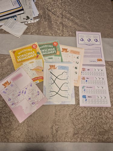 Rezensent zeigt die magischen Übungshefte des Sets. Die Hefte sind aufgeschlagen und zeigen verschiedene Aufgaben.
