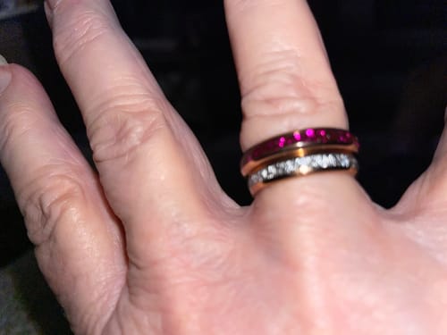 Close-up of a reviewer's hand wearing the Roselle ring with pink crystals stacked with another band.