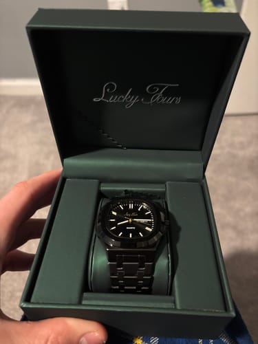 Customer showing the black Lucky Fours® Brone watch inside its dark green presentation box.