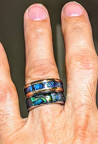 Customer wearing two stacked Nerium rings, showing the vibrant blue and green abalone inlay.