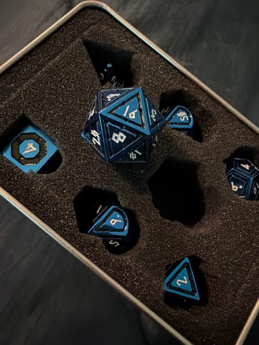 Customer's Cleric's Domain Black And Blue Metal Dice Set displayed in the open foam-lined storage tin.