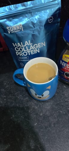 Reviewer's Halal Collagen Protein pouch on a counter next to a blue mug of coffee.