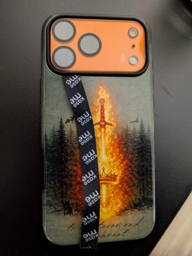 Reviewer's black Phone Loop attached to the back of a phone in a case with a flaming sword graphic.