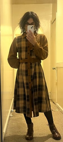 Reviewer in a hallway wearing the brown Plaid Corduroy Shirt Collar Dress with a matching belt, leggings, and boots.