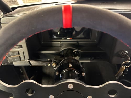 Customer's view of the black Steering Column Extension installed, bringing a racing-style steering wheel closer to the driver.