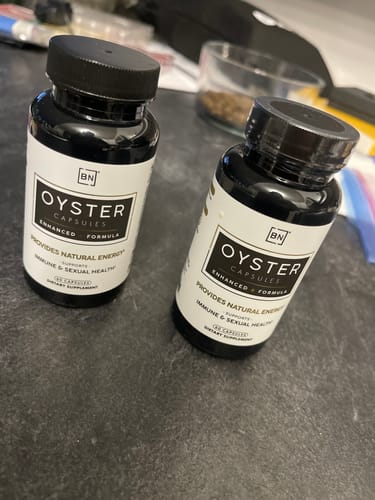 Customer's two black bottles of Oyster Capsules sitting on a dark countertop.