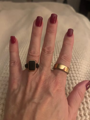 Customer's hand wearing the black rectangular Emerald Collection silicone ring with a gold-tone frame.
