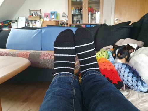 Anmelder slapper af på en sofa iført de sorte, stribede støttestrømper.