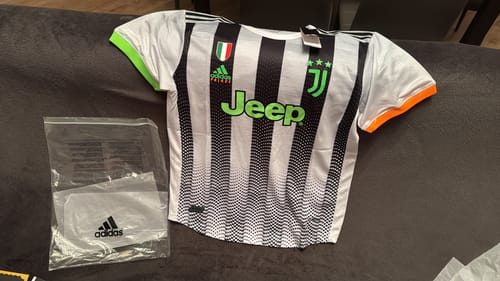 Il cliente mostra la maglia sballata, stesa su una superficie scura accanto alla sua confezione.