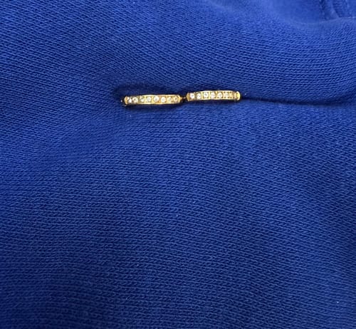 Close-up of a customer's shiny Eternity Hoop Earrings with crystals resting on a blue surface.