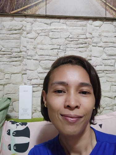 Reviewer with hydrated-looking skin smiling, with the Bad Skin™ Hydrating Ampoule box visible in the background.