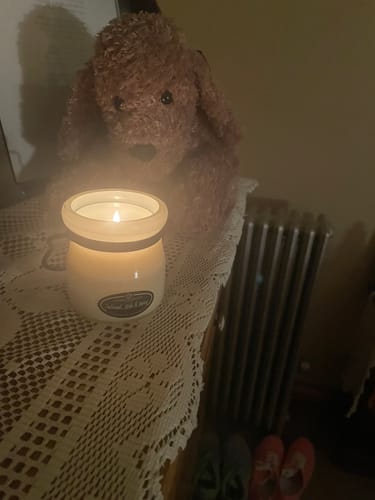 Customer's Oatmeal, Milk & Honey Candle lit on a table, casting a warm glow in a cozy room.