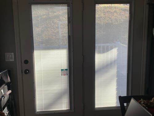 Customer's Raise & Lower Blinds installed on two glass doors, partially raised to show a snowy scene outside.