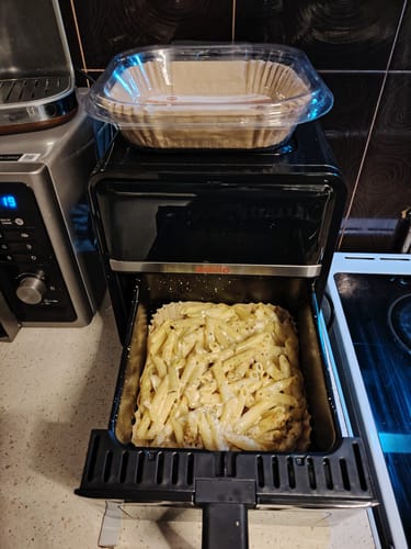 Client arătând o tavă cu paste preparate în friteuza Air Fryer Novio StonePro.