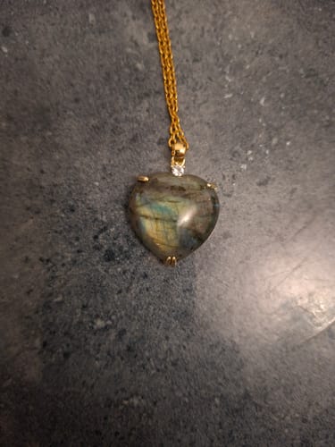 Photo d'un client du pendentif Coeur en labradorite. La pierre irisée est sur une chaîne dorée.
