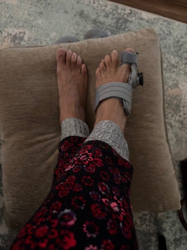Customer wearing the Treatmedy™ Bunion Fix on one foot while relaxing with their feet on a comfortable pillow.