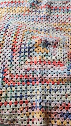Close-up of the reviewer's finished Hearthside Rainbow Blanket, showing the colorful granny square pattern without the fur border.