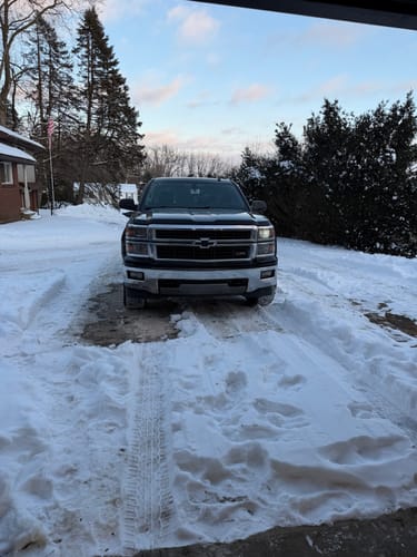 Customer's black truck in a snowy driveway before installing the 2-inch wheel spacers, showing a standard stance.